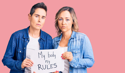 Couple of women holding my body my rules banner thinking attitude and sober expression looking self confident