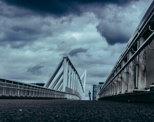 modern city architecture, footbridge under cloudy sky, with people silhouettes