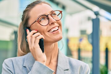 Young blonde businesswoman smiling happy talking on the smartphone at the city.