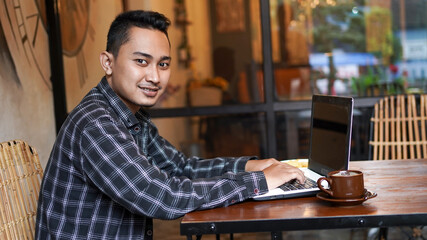 asian business man typing on laptop at cafe