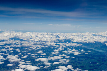 Aerial view of scattered clouds and snow-covered Pyrenees mountains on the horizon