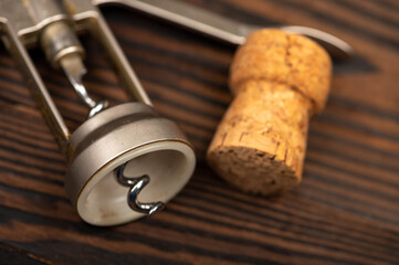 Corkscrew and corks from wine bottles on a wooden table.