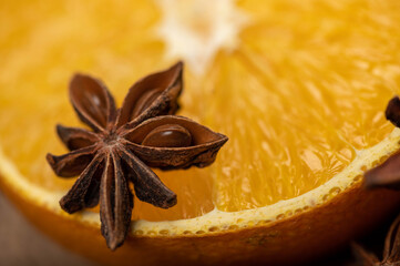 Half an orange and a star anise on a wooden table.