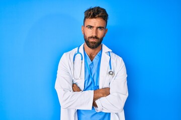 Young hispanic man wearing doctor uniform and stethoscope skeptic and nervous, disapproving expression on face with crossed arms. negative person.