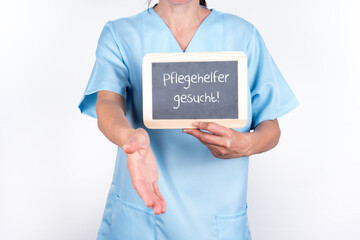 Pflegekraft mit einer Tafel Pflegehelfer gesucht