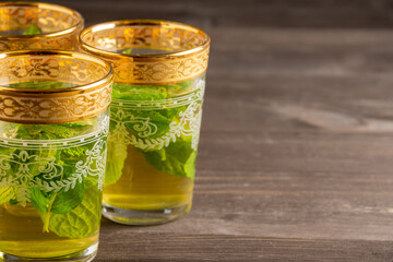 Close-up of three decorated mint tea glasses, selective focus, on wooden table, horizontal, with copy space