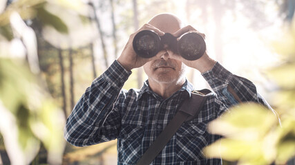 Tourist walking in a forest and using binoculars