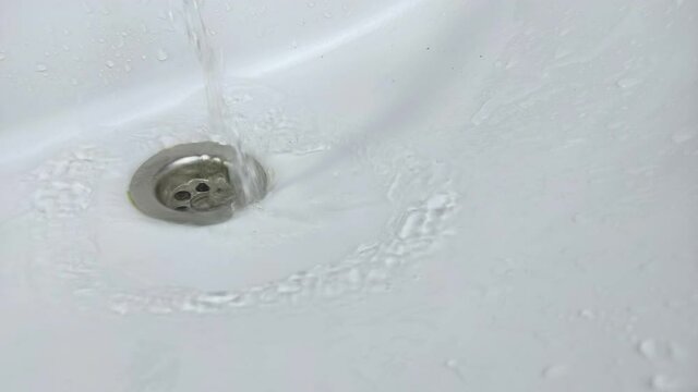 Water flows dynamically in the white bathroom sink.