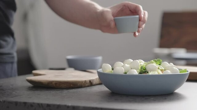 Slow motion man pour dressing over salad with kale, mozzarella, avocado and cherry tomatoes