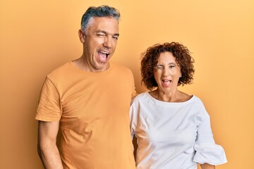 Beautiful middle age couple together wearing casual clothes winking looking at the camera with sexy...