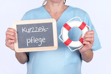Pflegekraft mit einem Rettungsring und einer Tafel auf der Kurzzeitpflege steht