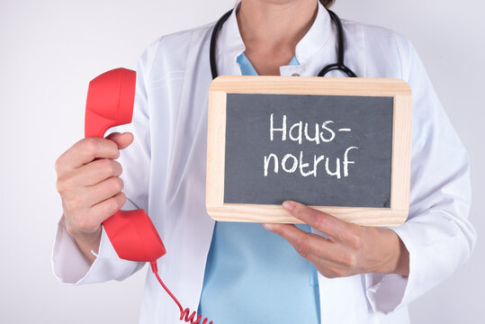 &Auml;rztin mit einem Telefon und einer Tafel auf der Hausnotruf steht