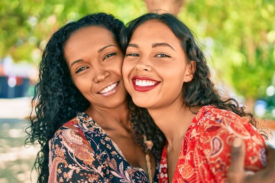 African american mother and daughter smiling happy hugging at the park.