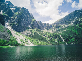 Beautiful alpine lake in the mountains, natural background, summer landscape with blue cloudy sky and reflection in crystal clear water, Morske Oko, Tatra Mountains, Zakopane, Poland