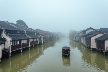 Fototapeta premium WUZHEN,CHINA-MARCH 6,2012: Ancient buildings along the canal. Morning fog over the city.