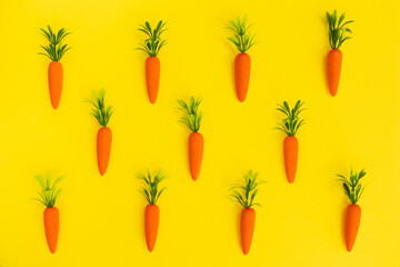 Easter pattern made with carrots on bright yellow background. Easter holiday concept. Flat lay.