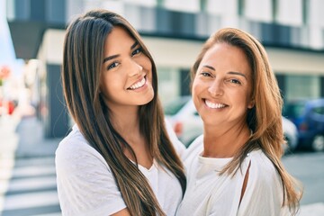 Fototapeta premium Beautiful hispanic mother and daughter smiling happy standing at the city.