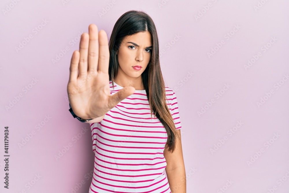 Poster young brunette woman wearing casual clothes over pink background doing stop sing with palm of the ha