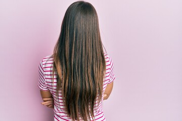 Young brunette woman wearing casual clothes over pink background standing backwards looking away with crossed arms