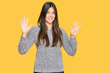 Young brunette woman wearing casual winter sweater showing and pointing up with fingers number nine...
