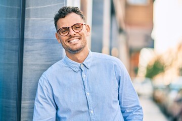 Naklejka premium Young hispanic businessman smiling happy standing at the city.