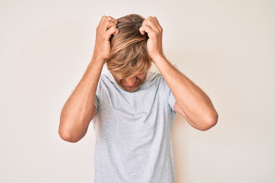 Young blond man wearing casual clothes suffering from headache desperate and stressed because pain and migraine. hands on head.