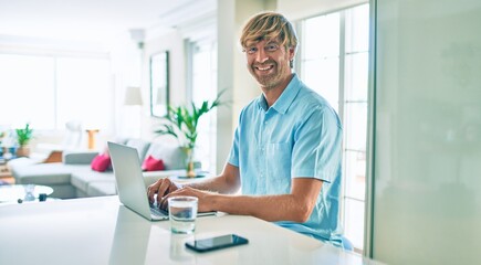 Naklejka na ściany i meble Young irish man smiling happy working using laptop sitting on the table at home.