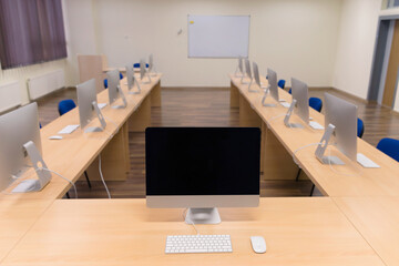 Modern office with computers on desks. Empty computer room in college. Interior of classroom with computers. Concept of corporate working space.