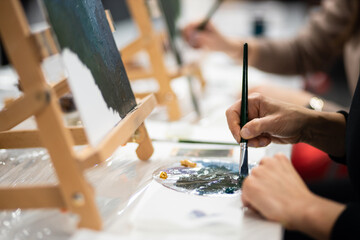 Fototapeta na wymiar A hand with a brush draws on a canvas with oil