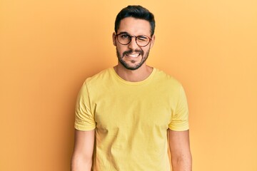 Obraz premium Young hispanic man wearing casual clothes and glasses winking looking at the camera with sexy expression, cheerful and happy face.