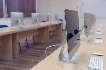 Modern office with computers on desks. Empty computer room in college. Interior of classroom with computers. Concept of corporate working space.