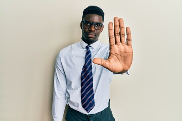 Handsome black man wearing glasses business shirt and tie doing stop sing with palm of the hand. warning expression with negative and serious gesture on the face.
