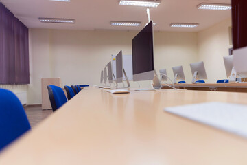 Modern office with computers on desks. Empty computer room in college. Interior of classroom with computers. Concept of corporate working space.