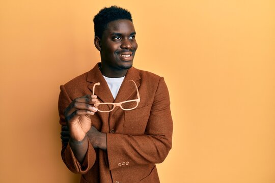 Handsome black man wearing elegant clothes and glasses smiling looking to the side and staring away thinking.