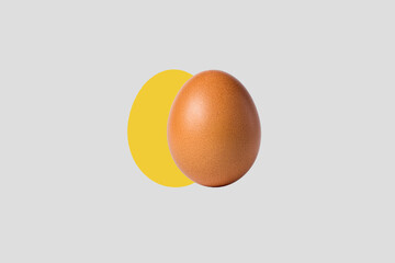 Chicken egg on a creative background. Yellow silhouette of an egg on a gray background. Egg on a yellow oval
