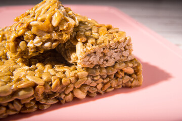 Kozinaki, seed bars and icing sugar on a pink background, close-up, copy space,