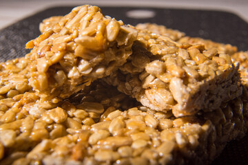 Kozinaki, seed bars and icing sugar on a black background, close-up