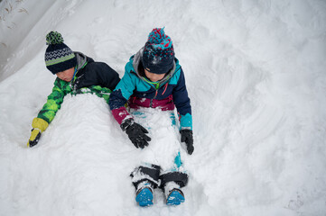 Fototapeta na wymiar Children playing in snow. Two Asian children buried in snow in winter. Happy childhood. Zermatt, Switzerland.