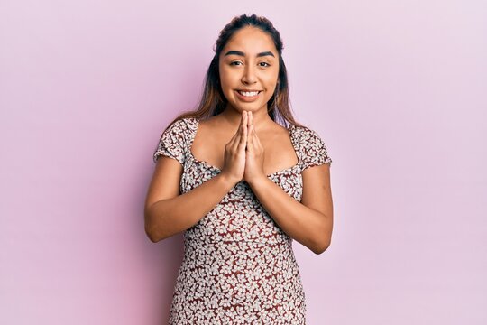 Young latin woman wearing casual clothes praying with hands together asking for forgiveness smiling confident.