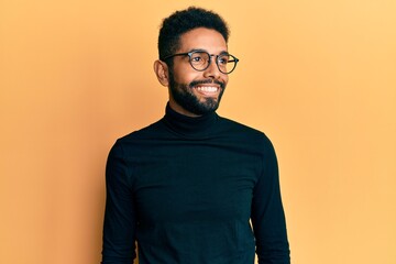Handsome hispanic man with beard wearing turtleneck sweater looking to side, relax profile pose...