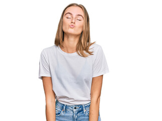 Fototapeta premium Beautiful young blonde woman wearing casual white t shirt looking at the camera blowing a kiss on air being lovely and sexy. love expression.