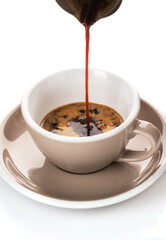 coffee is poured into a cup on a white background 