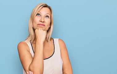 Middle age caucasian woman wearing casual clothes with hand on chin thinking about question, pensive expression. smiling and thoughtful face. doubt concept.