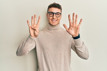 Hispanic young man wearing casual turtleneck sweater showing and pointing up with fingers number...
