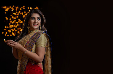 woman in  saree holding diya and smiling	