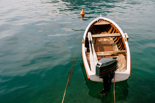 Close-up of a fishing boat with oars and a detachable motor on the water.