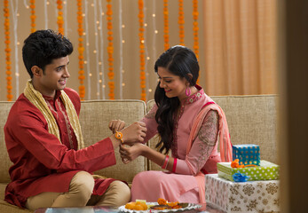 Young Girl Tying rakhi to her brother on Raksha Bandhan	
