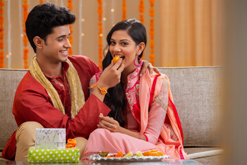 brother stuffing sweets in sister's mouth	