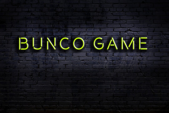 Neon sign. Word bunco game against brick wall. Night view