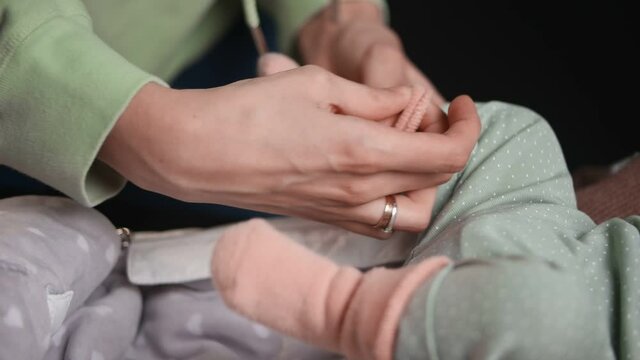 Mom puts on socks for her baby. Close-up.